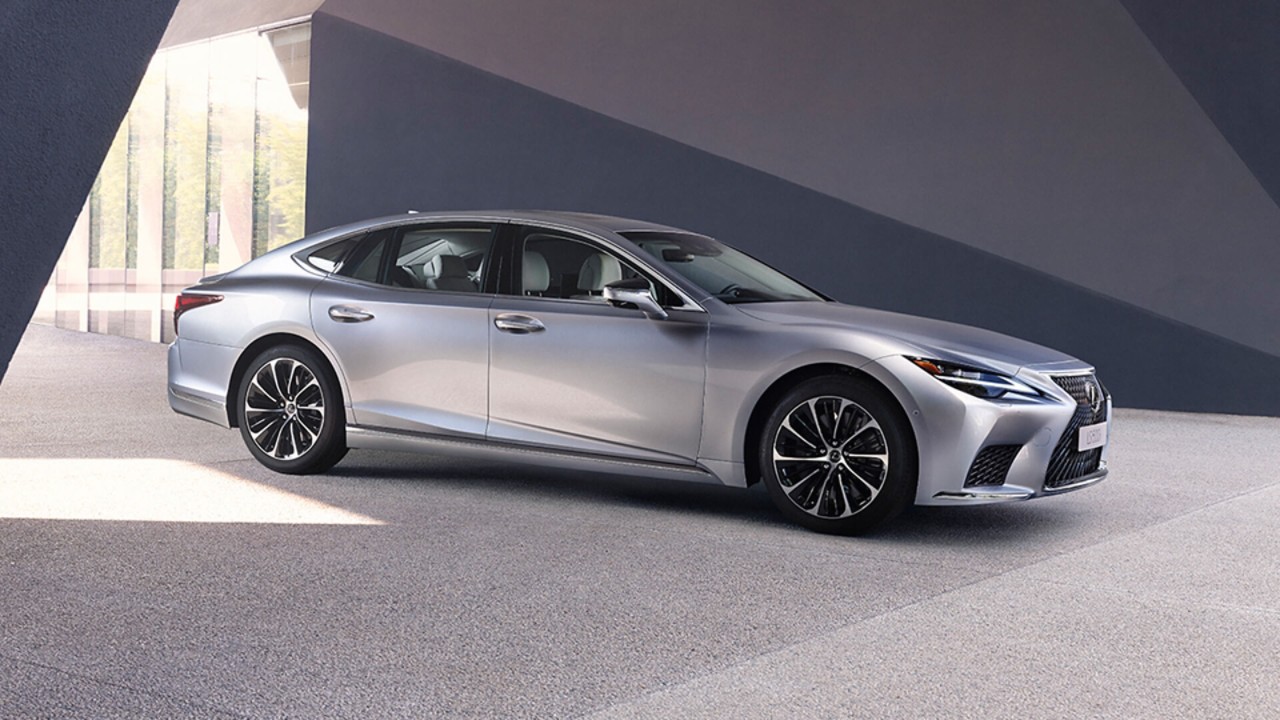 A man and woman stood next to a parked Lexus LS