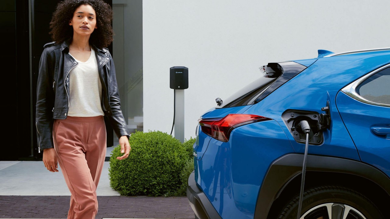 A woman walking towards a Lexus UX 300e 