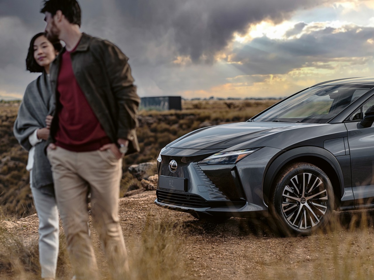 A man and woman walking away from a Lexus RZ