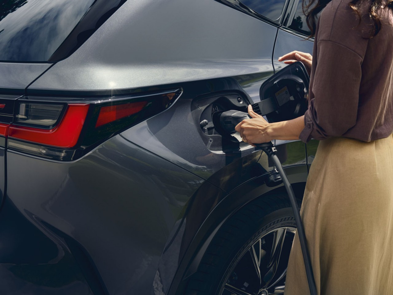 A woman plugging in a charger into a Lexus NX 